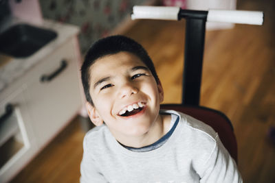 High angle view of happy disabled boy sitting on wheelchair at home