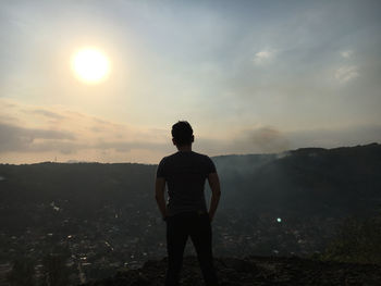 Rear view of man standing on mountain during sunset