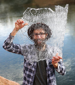 Portrait of man in water splashing against sky