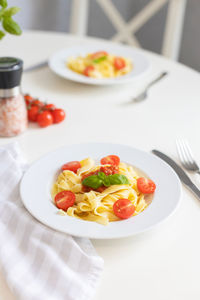 Italian pasta with cherry tomatoes, tomato sauce and cheese, garnished with a sprig of basil. 