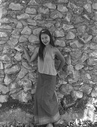 Portrait of smiling woman standing against stone wall