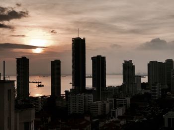 Modern buildings in city against sky during sunset
