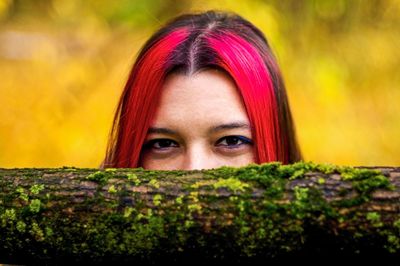 Close-up portrait of beautiful young woman by tree trunk