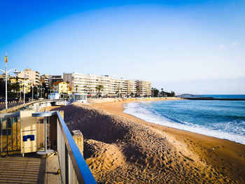 Buildings by sea against clear blue sky