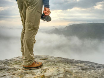 Landscape photograper with camera ready in hand. man climbed up on exposed rock for fall photos 