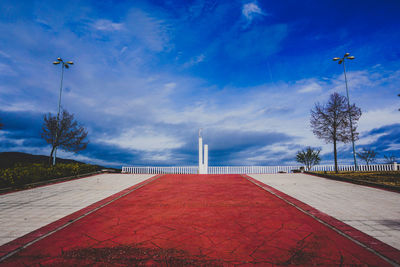 Footpath by sea against blue sky