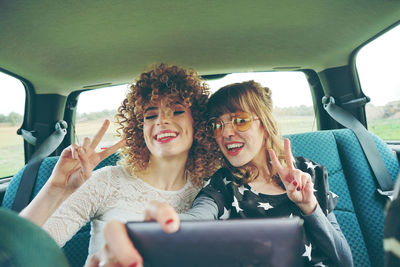 Cheerful female friends taking selfie while sitting in car