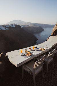 Chairs and tables on shore against sky