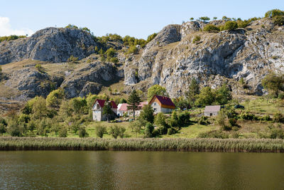 Buildings by river against mountain