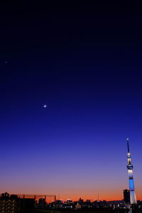 Illuminated cityscape against clear blue sky at night