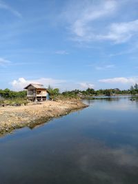 House by lake against sky