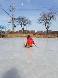 Rear view of boy sitting in ice rink