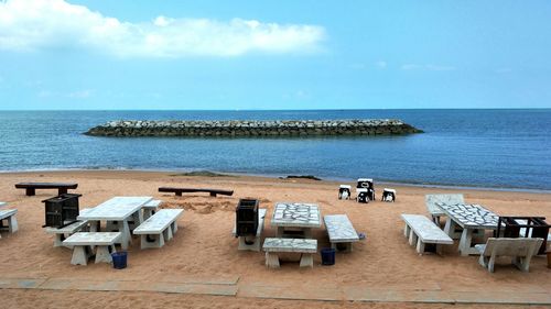 Chairs and table on beach against sky