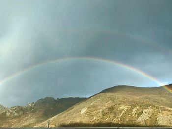 Scenic view of rainbow over mountains against sky