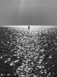 Silhouette person standing in sea against sky