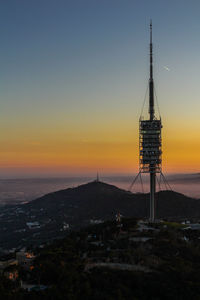 Tower by sea against sky during sunset