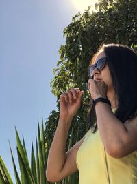 Midsection of woman holding sunglasses against sky