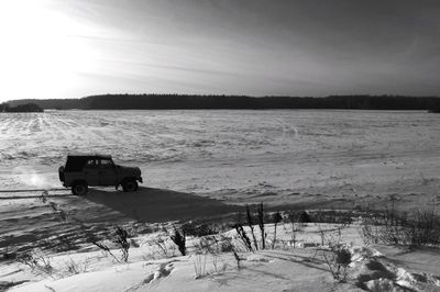 High angle view of off-road vehicle on snow covered field against sky