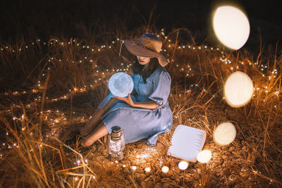 Woman sitting on field at night