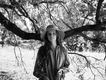 Young woman standing against trees