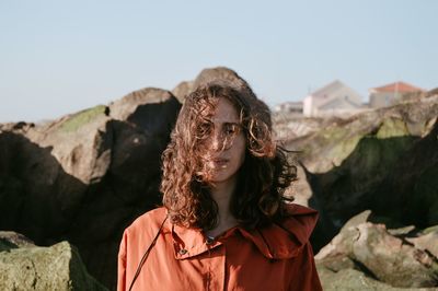 Portrait of young woman standing against rocks