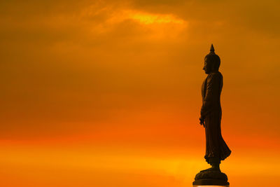 Low angle view of statue against orange sky