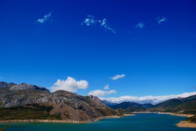 Scenic view of lake by mountains against blue sky