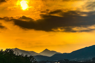 Scenic view of dramatic sky over silhouette mountains during sunset