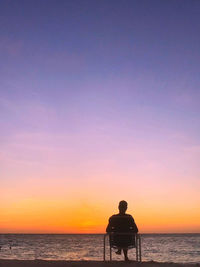 Silhouette people looking at sea against sky during sunset