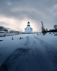 Snow covered cemetery against cloudy sky