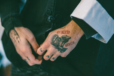 Midsection of tattooed man buttoning shirt