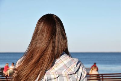 Rear view of woman with brown hair against sea