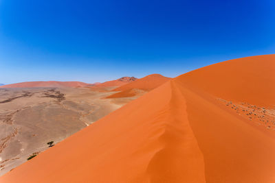 Scenic view of desert against clear blue sky