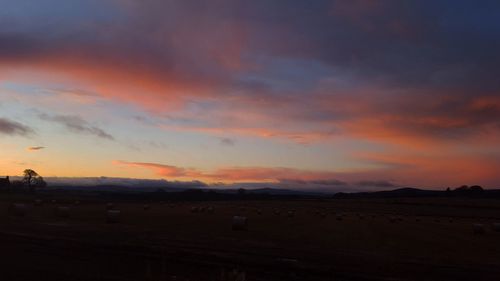 Silhouette landscape against cloudy sky during sunset