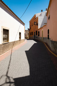 Footpath amidst buildings in city on sunny day