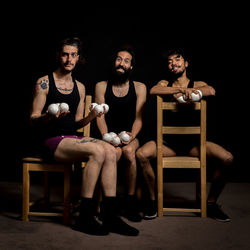 Portrait of young jugglers sitting on chairs with balls on stage