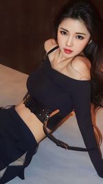 Portrait of young woman standing against wall