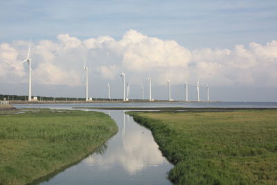 Windmills on field against sky