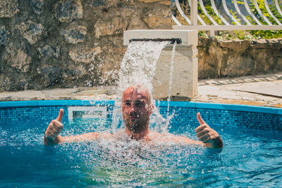 Man gesturing by fountain swimming in pool