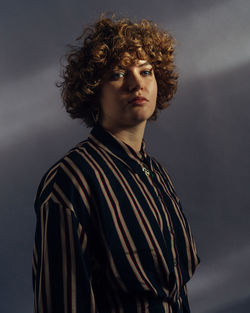 Portrait of teenage girl standing against gray background