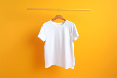 Close-up of clothes hanging against yellow background