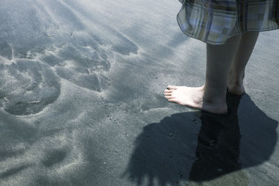 Low section of woman standing on sand at beach