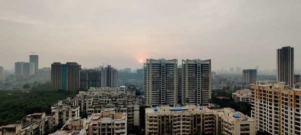 Modern buildings in city against sky during sunset