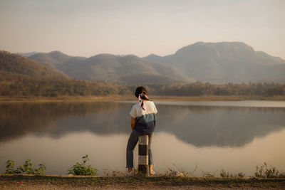 Rear view of man looking at lake against mountain