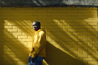 Portrait of man standing by brick wall