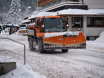 Road vehicle snowplow in action on whitewashed roads during a snowy day.