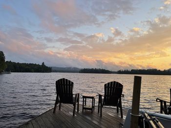 Empty seats in lake against sky during sunset