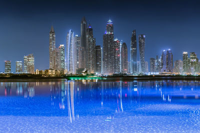 Illuminated buildings by swimming pool at night