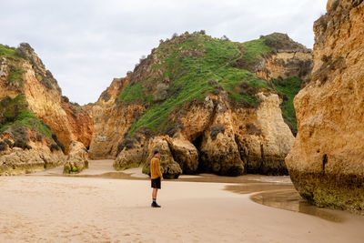 Rear view of woman walking on beach against sky