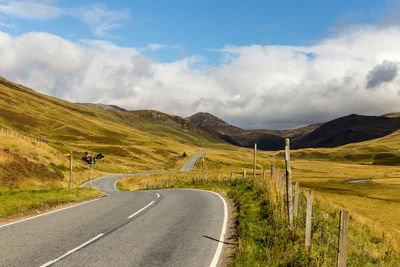 Road amidst field against sky